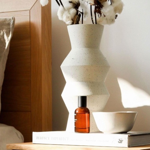 a vase with cotton stems on a bedside table